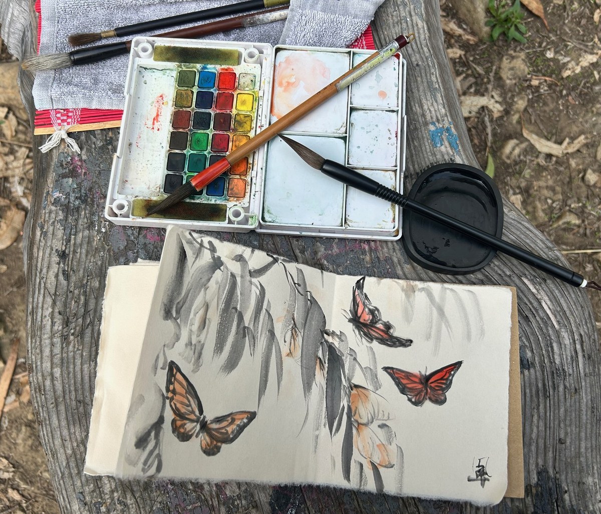 Plein-air sumi-e setup — sketchbook, palette and brushes on a tree stump, 2025, Fumiyo Yoshikawa